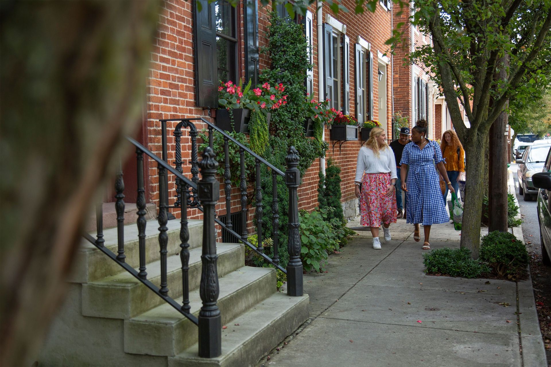 Students walking down a tree-lined sidewalk in downtown Carlisle.