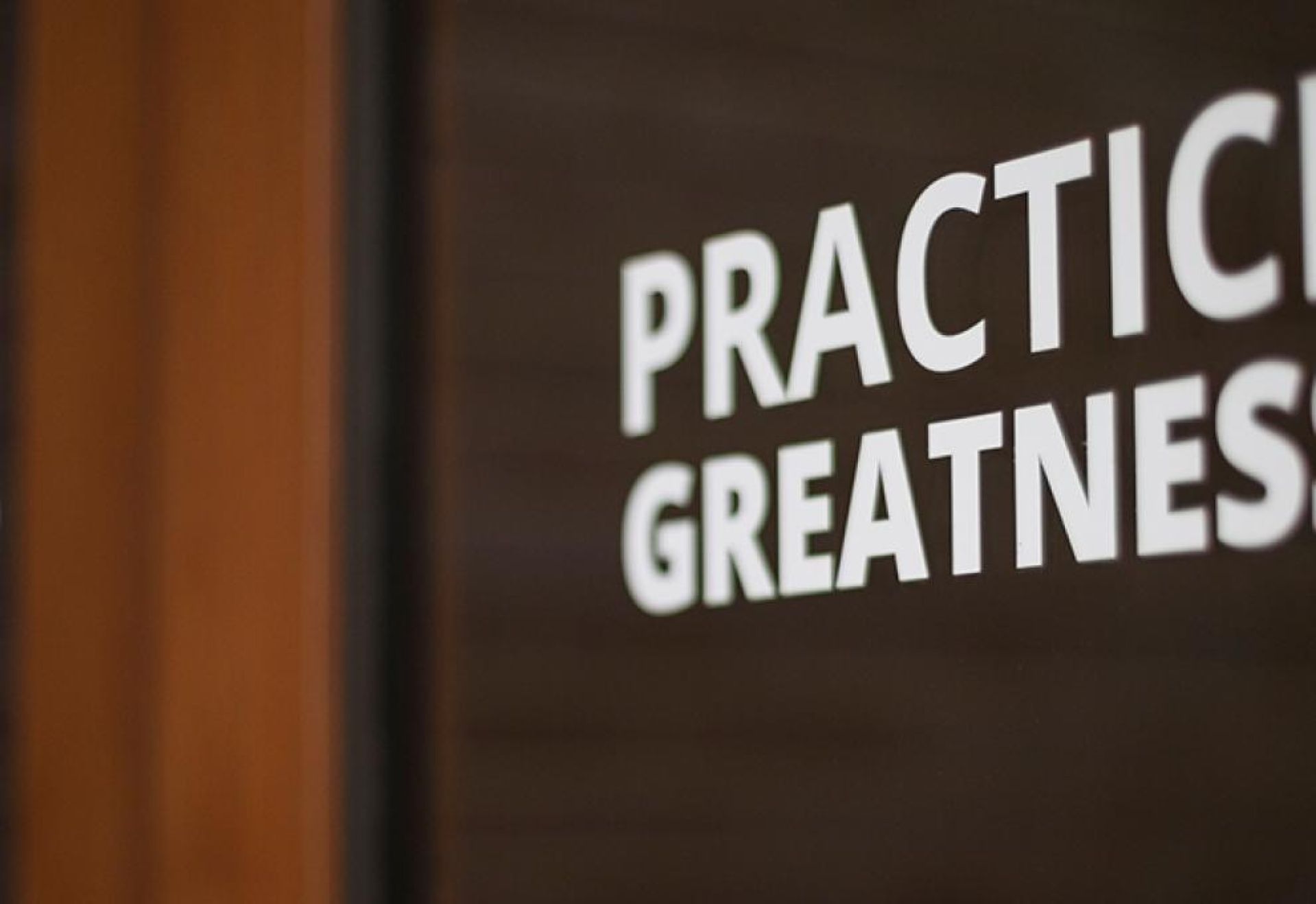 A door with partial words "Practice Greatness"