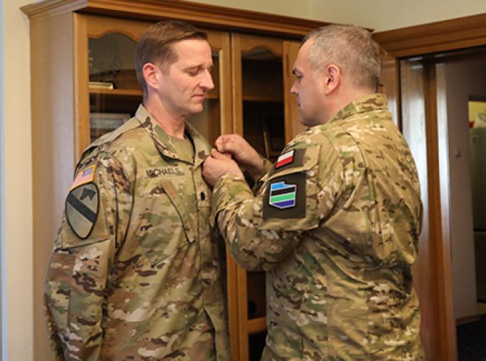 One military man receiving a pin from another.